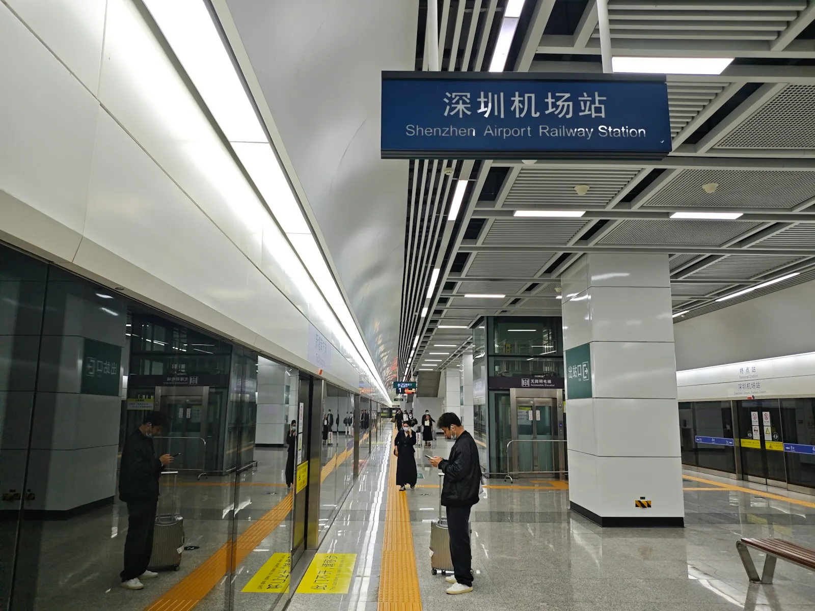 Shenzhen Airport Railway Station — bilingual signage and a phone-in-hand traveler, the kind of transit hub where Alipay's Travel Card mini-program is built to work
