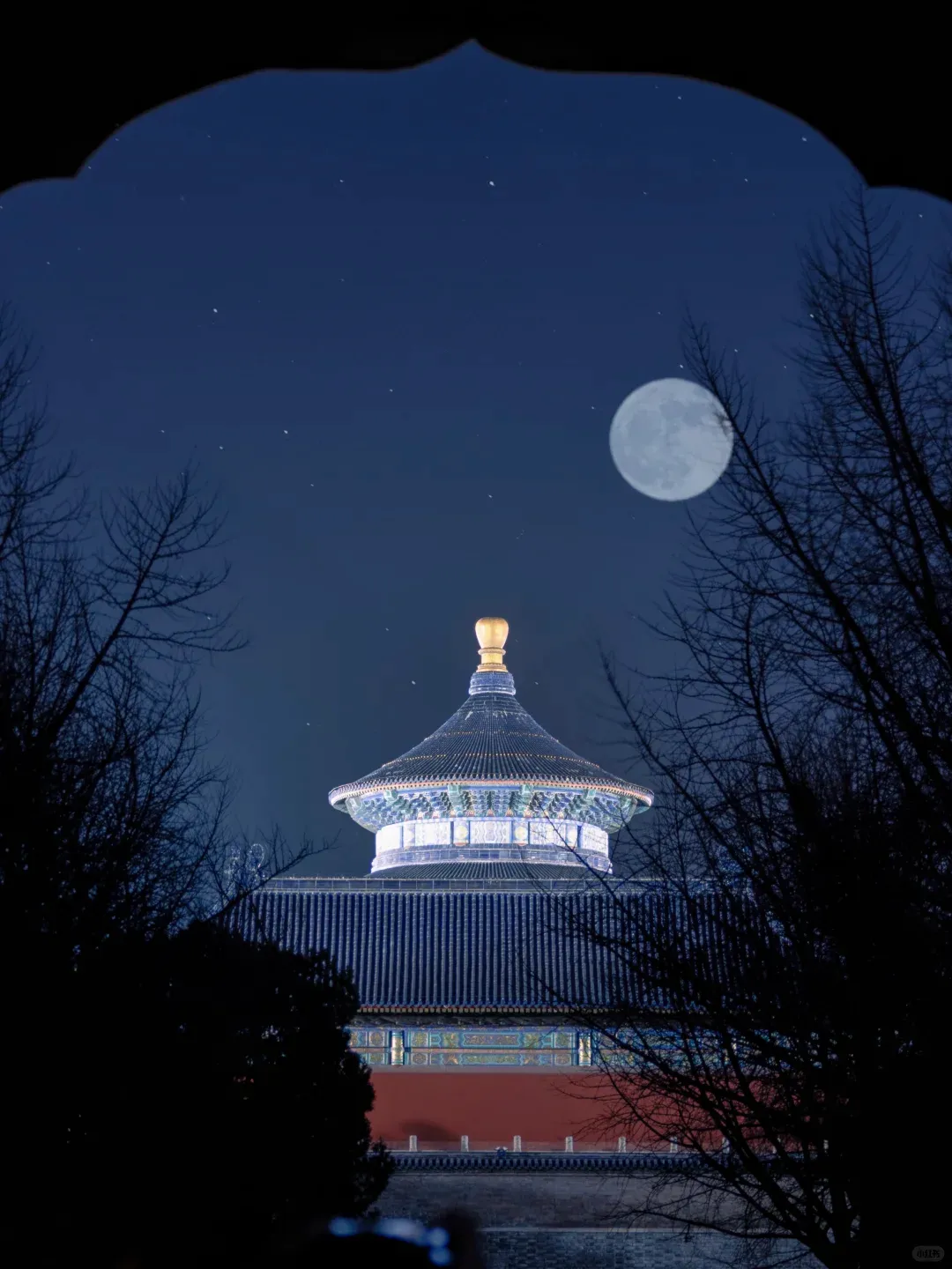 The Temple of Heaven's triple-tiered blue roof glowing under a full moon, framed by a stone gateway