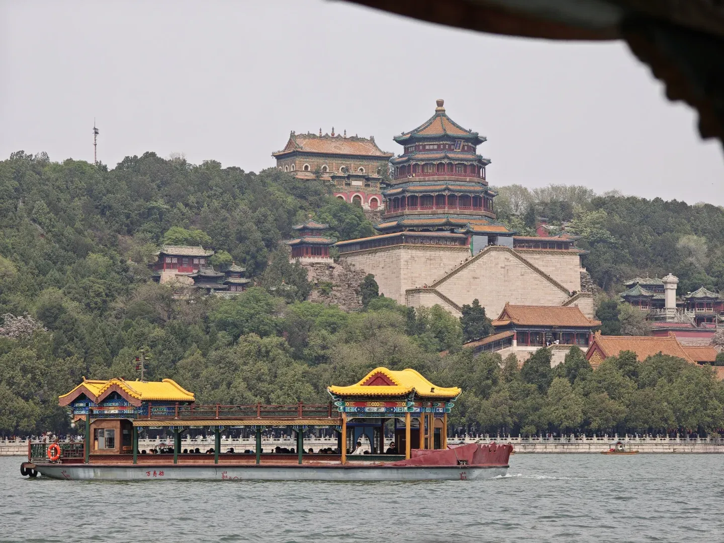 A pleasure boat crossing Kunming Lake in front of the Summer Palace's temple-covered hill
