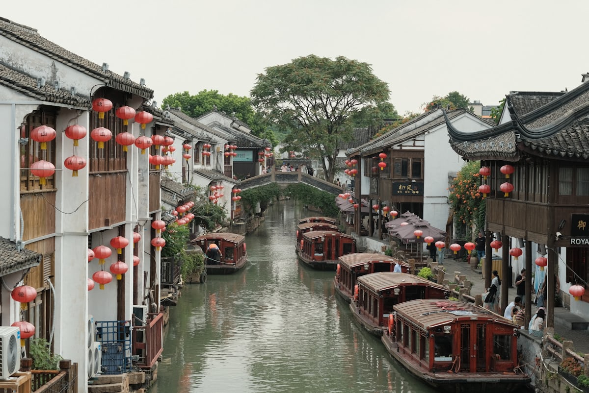 Whitewashed houses and red lanterns above a boat-filled canal in Suzhou's old town — the most atmospheric stretch of the day