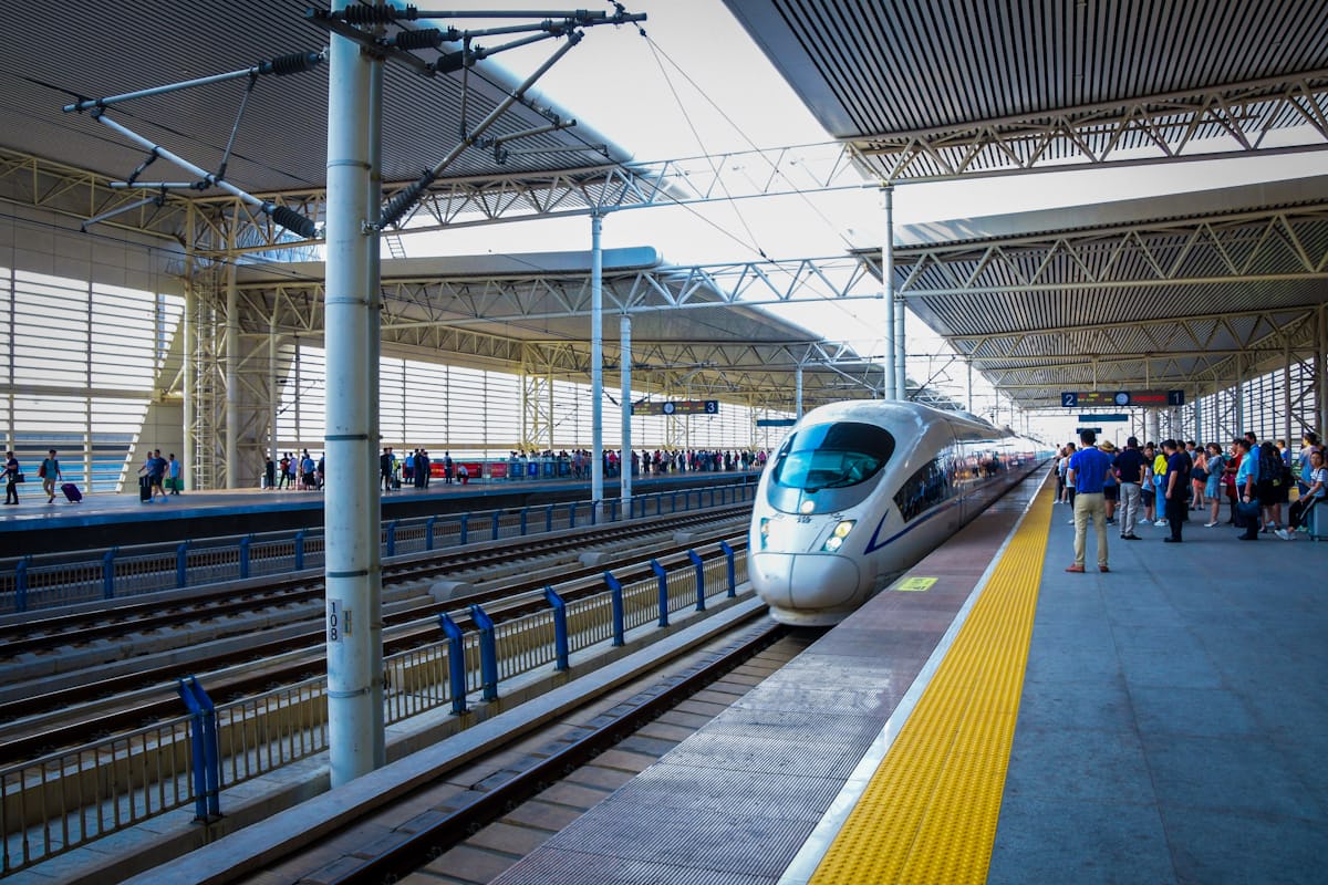 A CRH bullet train pulls into a Beijing station as passengers wait — high-speed rail covers the 1,200 km to Xi'an in about 4.5 hours