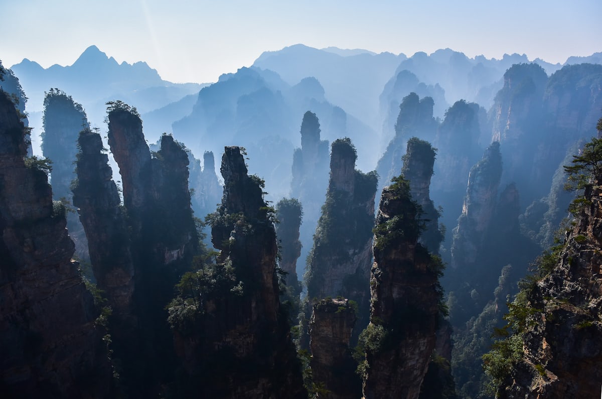 Mist drifting between the quartz-sandstone pillars of Yuanjiajie — the landscape that inspired Avatar's floating mountains