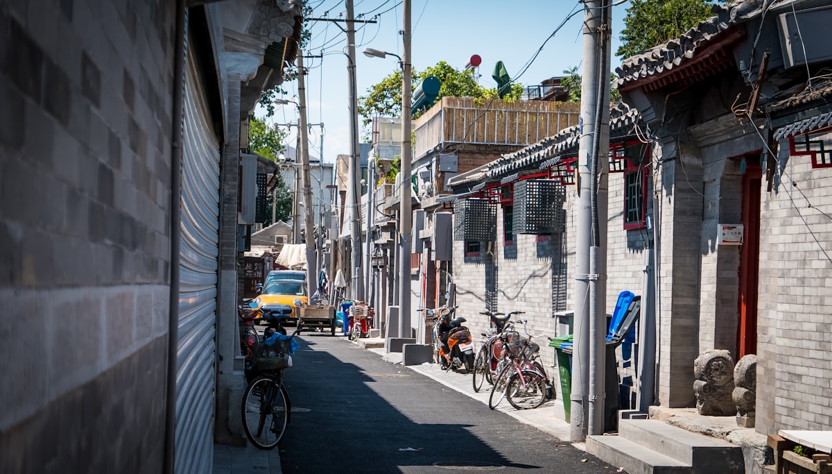 A quiet grey-brick hutong lane — bikes, courtyard doors, and everyday Beijing