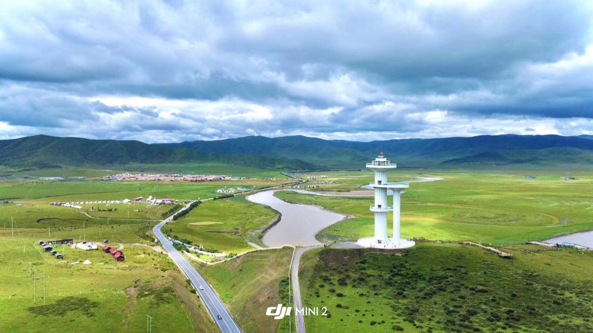 Drone shot from the ridge: the eastern Tibetan Plateau opens into grassland, a winding river and endless horizon